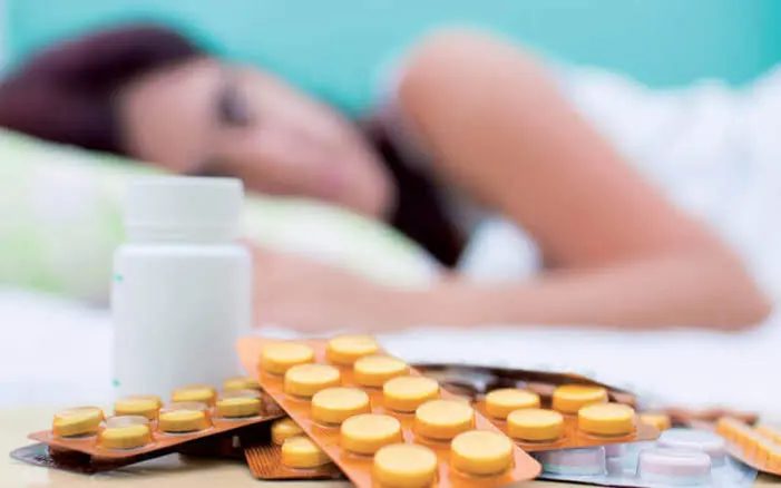 Automédication : femme allongée près de boîtes de médicaments - Clinique La Rose